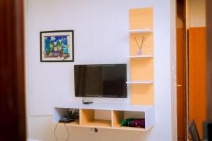 een woonkamer met een tv aan een witte muur bij Emerald Villa in Kigali