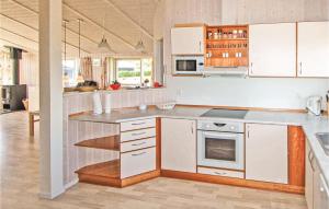 La cuisine est équipée de placards blancs et d'un four avec plaques de cuisson. dans l'établissement 3 Bedroom Beautiful Home In Juelsminde, à Sønderby