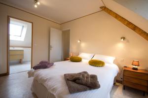 Un dormitorio con una gran cama blanca con almohadas amarillas. en Traditional Brittany Home, en Quessoy