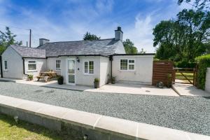 a white cottage with a gravel driveway at Tyddyn Waen in Llanddona