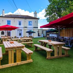 un grupo de mesas de picnic con sombrillas rojas en The Railway Inn, en Brixham