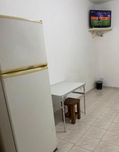 Cette chambre comprend un réfrigérateur, une table et une télévision. dans l'établissement Lindo kit na quadra da praia, à Santos