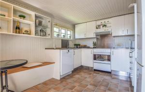 ヒュールスミンネにあるAmazing Home In Juelsminde With 3 Bedrooms And Wifiの白いキャビネットとテーブル付きのキッチンが備わります。