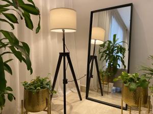 una lámpara de pie y un espejo en una habitación con plantas en الرياض البوليفارد شقق عبيه Vip الفاخره en Riad