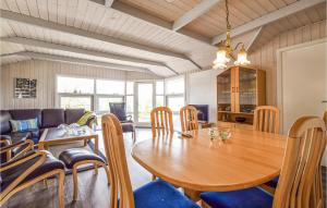 a dining room with a wooden table and chairs at Beautiful Home In Brkop With 3 Bedrooms, Sauna And Wifi in Brejning