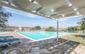 a swimming pool with a patio with chairs and an umbrella at Tenuta Licitra in Ragusa