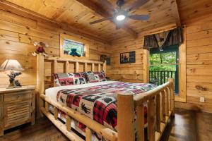 una camera da letto in stile baita di tronchi con letto e ventilatore a soffitto di Miss Beehaven a Sevierville