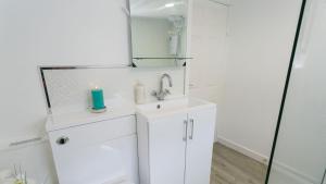 a white bathroom with a sink and a mirror at Borth Bach in Rhosneigr