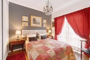 een slaapkamer met een bed met rode gordijnen en een kroonluchter bij Little Paradise 25 min from Lisbon in Azeitao +30 foto's