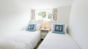 two twin beds in a white room with a window at Borth Bach in Rhosneigr