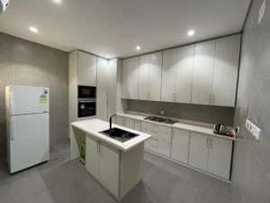 a kitchen with white cabinets and a white refrigerator at LADAN APARTMENT in AlUla