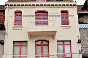 un edificio con ventanas rojas y balcón en Coeur du centre ville, joli 50m2 de charme, wifi, en Le Touquet-Paris-Plage