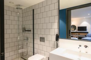 a bathroom with a sink and a shower with a mirror at NEO KVL Hotel by TASIGO in Oisterwijk