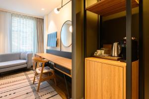 a hotel room with a desk and a couch at NEO KVL Hotel by TASIGO in Oisterwijk