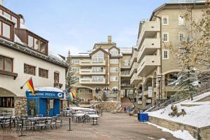 a group of buildings with tables and chairs in a courtyard at Ski, In Ski Out 3 Bedroom Vacation Condo With Resort Amenities That Include Exercise Center, Indoor Pool, And Hot Tubs in Beaver Creek