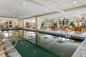 an indoor swimming pool in a house with tables and chairs at Ski, In Ski Out 3 Bedroom Vacation Condo With Resort Amenities That Include Exercise Center, Indoor Pool, And Hot Tubs in Beaver Creek