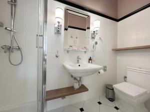 La salle de bains blanche est pourvue d'un lavabo et de toilettes. dans l'établissement Pollera, à Cracovie