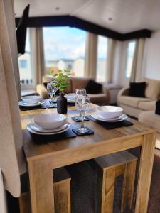 a wooden table with plates and wine glasses on it at Golden Palm Getaway's PG143 in Skegness