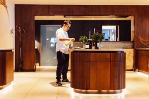 a man standing at a bar with a bottle of wine at Hotel Römerhof Superior in Obertauern