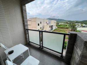 einen Balkon mit einem weißen Stuhl und einem Tisch in der Unterkunft Big Nose Inn in Altstadt von Hengchun