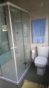 a bathroom with a toilet and a shower with a blue towel at Caiowa Floripa guesthouse in Florianópolis
