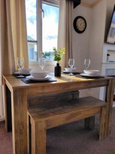 a wooden table with glasses and plates on it at Golden Palm Getaway's PG143 in Skegness