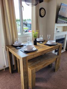 a wooden table with plates and wine glasses on it at Golden Palm Getaway's PG143 in Skegness