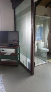 a glass room with a bathroom with a toilet at Caiowa Floripa guesthouse in Florianópolis