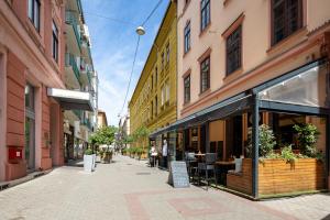 una calle de la ciudad con edificios y una cafetería en la acera en Dessewffy Premium Apartment en Budapest