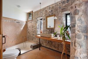 a bathroom with a stone wall with a sink and a toilet at Dependance in Costiera Amalfitana in Cava deʼ Tirreni