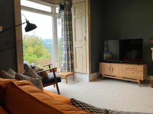 a living room with a tv and a large window at Kennet House in Ludlow +8 photos