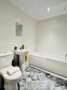 a bathroom with a toilet and a sink and a tub at Bright and Spacious 2 bed apt - sleeps up to 6 in Manchester
