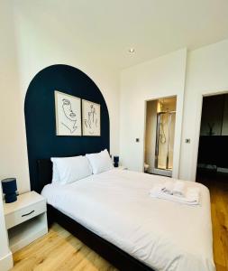 a bedroom with a large white bed with a blue headboard at Bright and Spacious 2 bed apt - sleeps up to 6 in Manchester