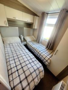 two beds in a small room with a window at Golden Palm Getaway's PG143 in Skegness