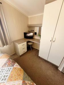 een slaapkamer met een bed en een bureau met een computer bij Golden Palm Getaway's PG143 in Skegness
