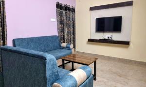 sala de estar con 2 sillas y TV en Sannidhi Service Apartments, en Tirupati