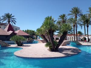 a resort with palm trees and a swimming pool at Alojamiento con Piscina y chiringuito Denia in Denia