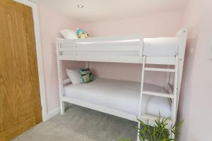 a white bunk bed in a room with a ladder at Cae Coch in Newborough
