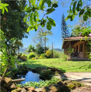 un jardín con un estanque frente a una casa en Sítio Completo, na estrada de Aldeia Velha, com rio a frente da porteira, en Silva Jardim