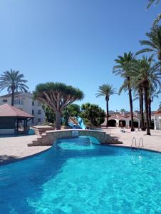 a swimming pool at a resort with palm trees at Alojamiento con Piscina y chiringuito Denia in Denia