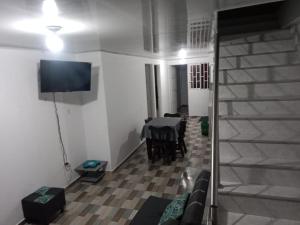 a living room with a couch and a table and a television at La casa de los viajeros Jazmin in San Gil