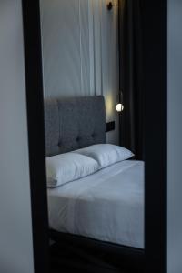 una camera da letto con un letto con lenzuola bianche e uno specchio di HOTEL CORONA DE PADRÓN a Padrón