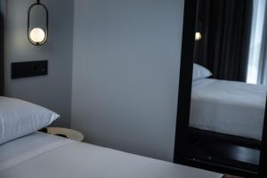 una camera con due letti e uno specchio di HOTEL CORONA DE PADRÓN a Padrón