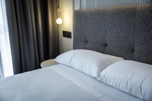 a bed with a white pillow and a headboard at HOTEL CORONA DE PADRÓN in Padrón