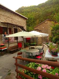 un patio al aire libre con mesas, sombrillas y flores en CASE CARMELI - Primula, en Triora