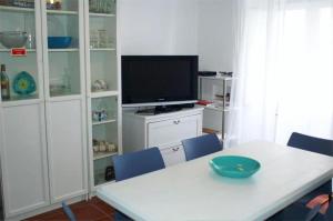 uma sala de jantar com uma mesa branca e uma televisão em SwordFish Casa da Luz em Peniche