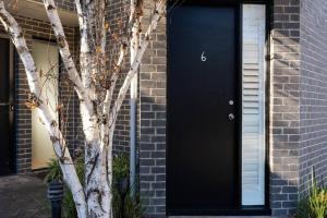 une porte noire sur le côté d'une maison en briques dans l'établissement Secluded Bayside Oasis: BR w/ Spa-like BA, à Parkdale