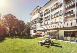 un edificio con bancos en el césped frente a él en Park Igls - Medical Spa Resort, en Innsbruck