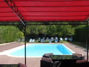 una piscina con sombrilla y sillas rojas en Domaine Du Val De Cèze, en Bagnols-sur-Cèze