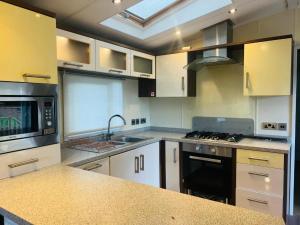 cocina con fregadero y fogones horno superior en ABRIDGE PANORAMIC House, en Theydon Bois